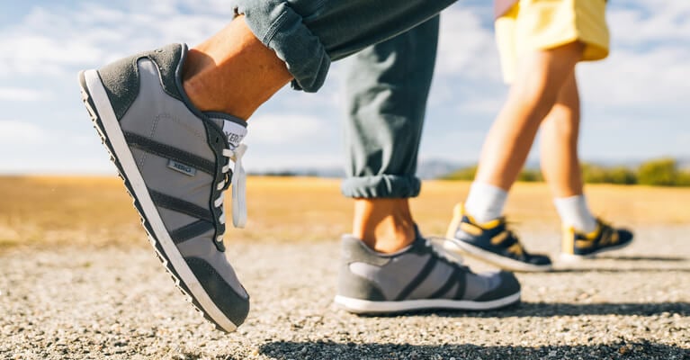 Two walkers heading down a sunny path in their Wynn Xero Shoes.